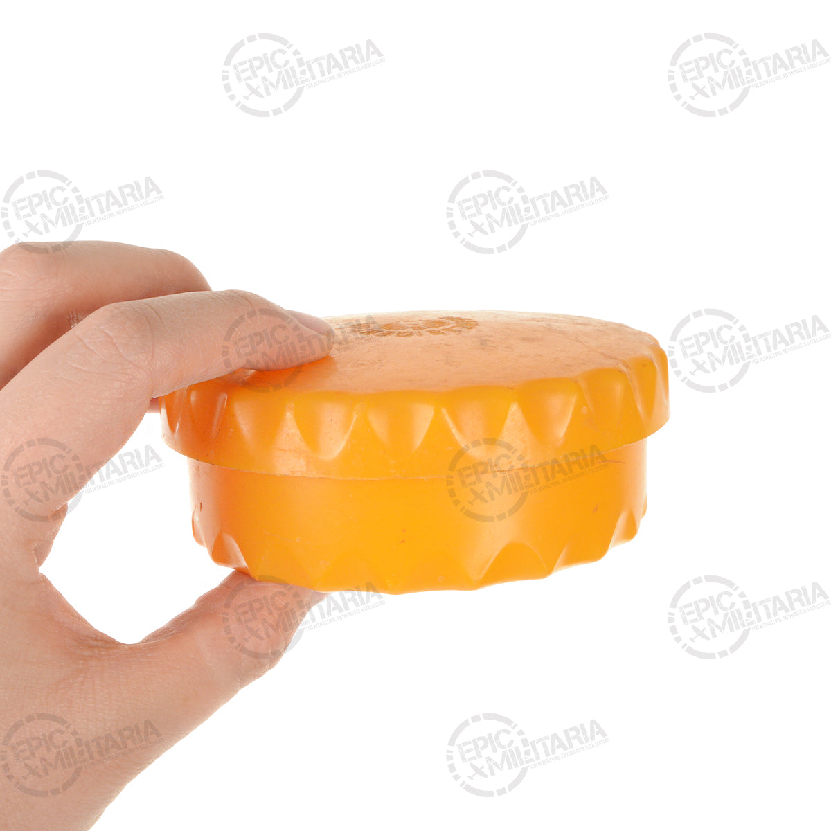 Hand holding a compact, orange Austrian Army butter dish, illustrating its small size for field rations and portability.