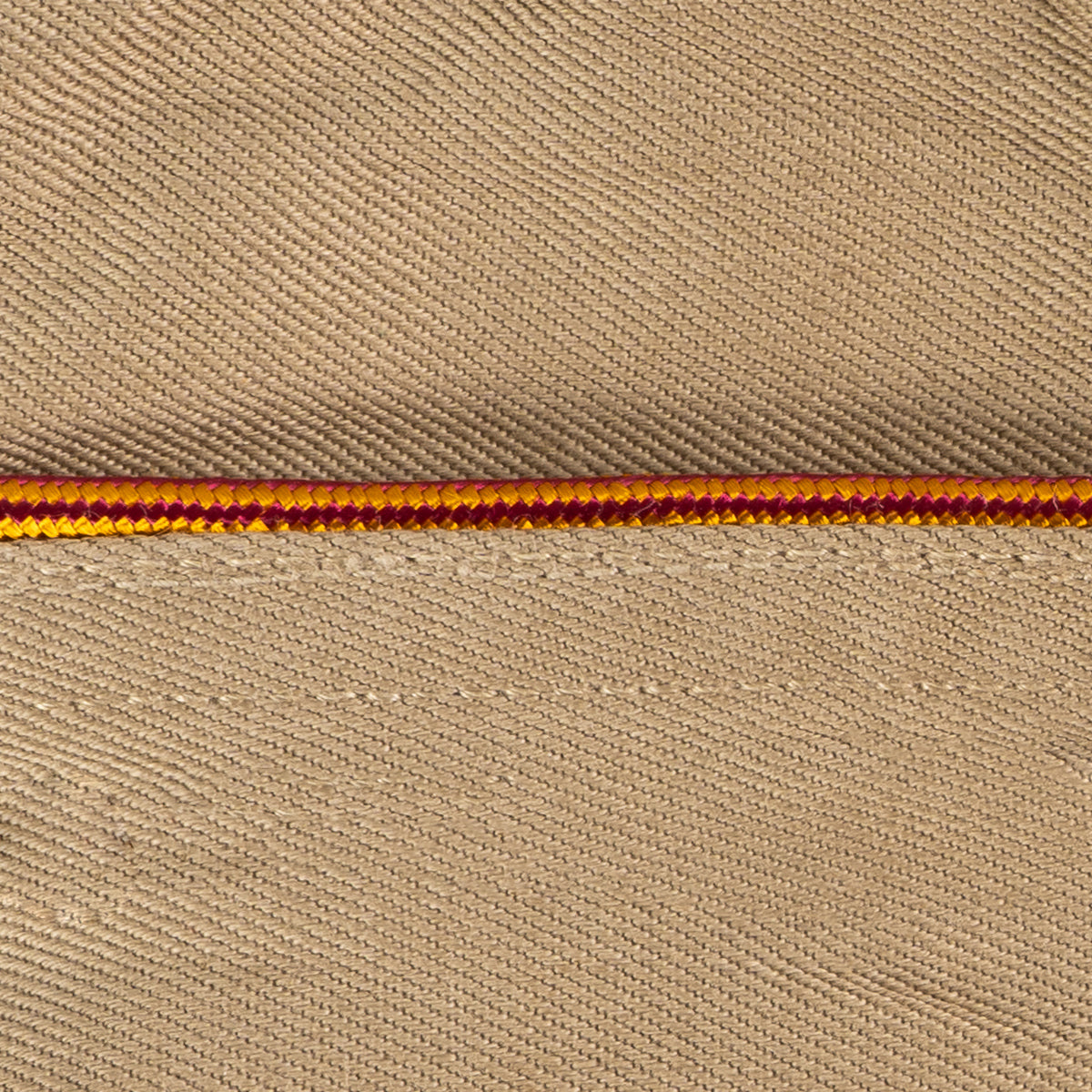 Macro shot of two-tone burgundy and yellow braided piping detail on a collector's US Army Garrison Cap.
