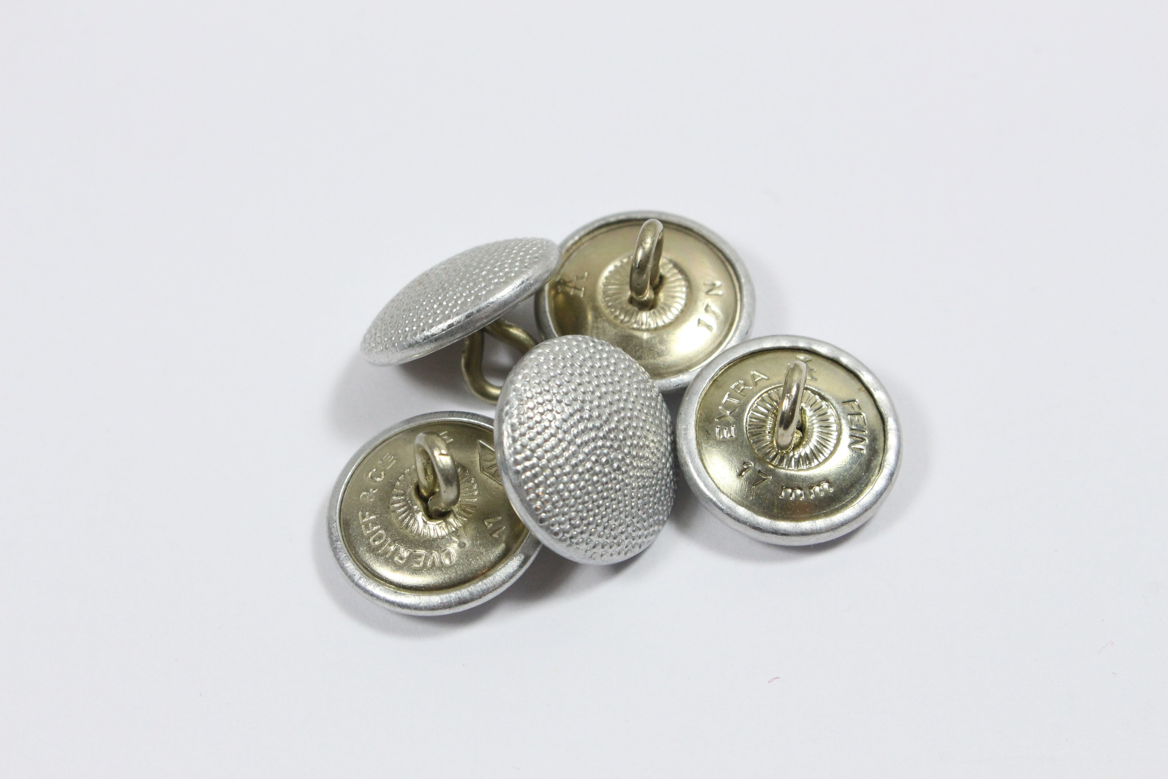 A pile of 17mm silver pebbled German shoulder board buttons with visible shank loops and maker marks including EXTRA FEIN and OVERHOFF & CIE.