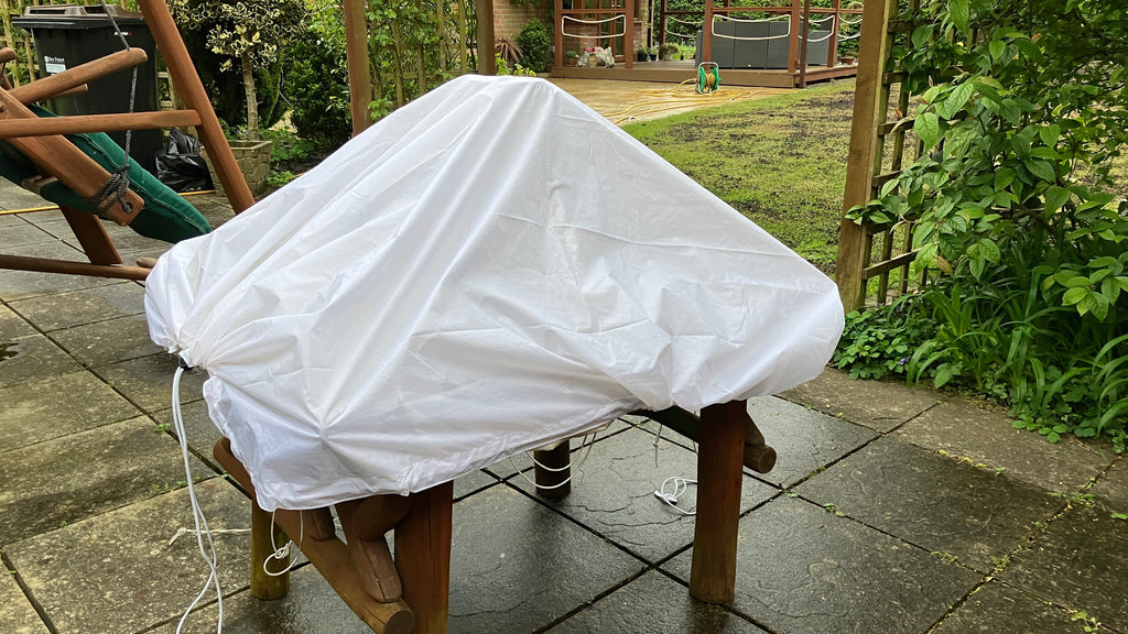 Side profile of a white utility sheet covering a garden stool, demonstrating its waterproof protective coverage.