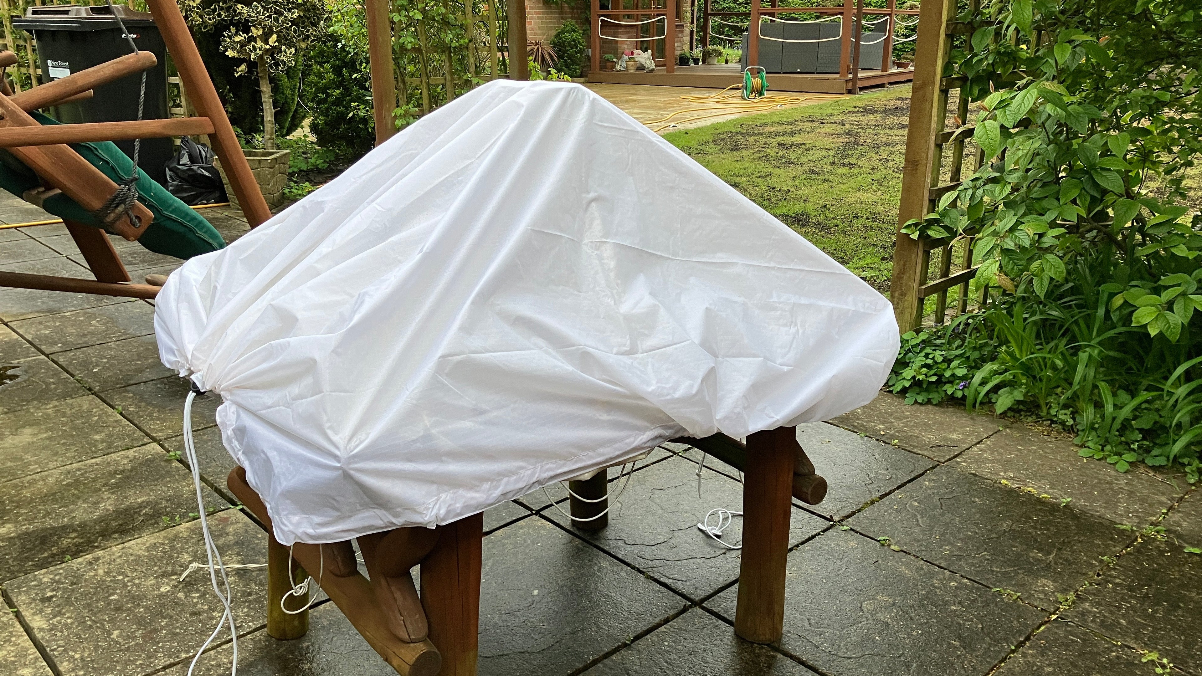 Side profile of a white utility sheet covering a garden stool, demonstrating its waterproof protective coverage.