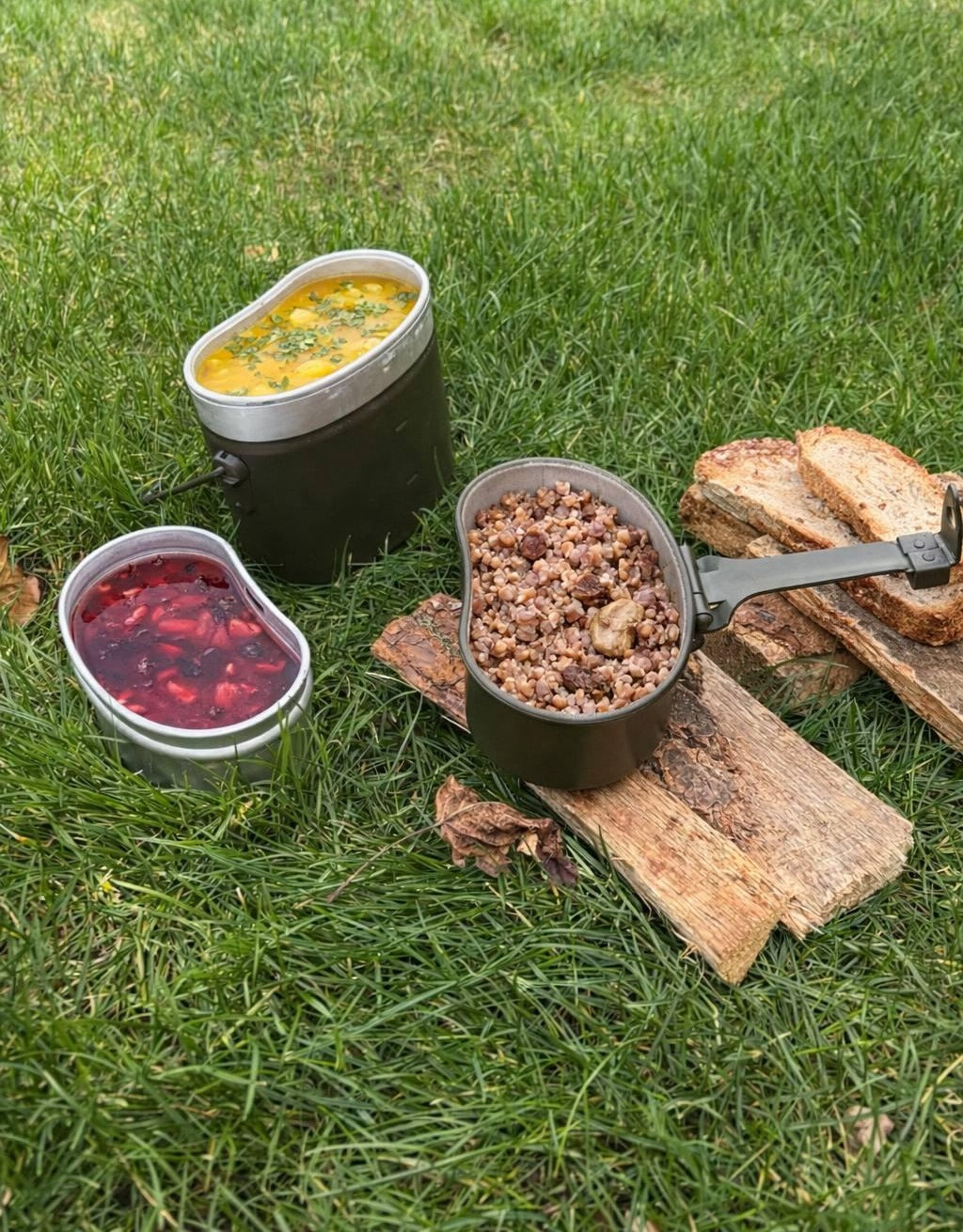 Italian Army mess tins used outdoors in grass, filled with food to demonstrate their utility for camping and bushcraft.