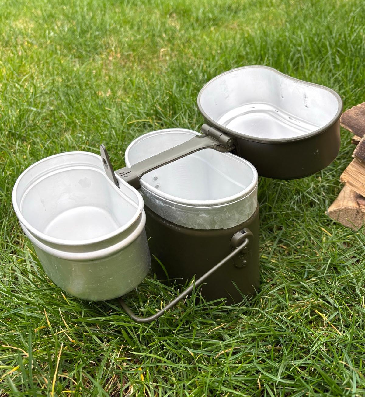 Two Italian Army mess tins separated to show the versatile cooking configuration with folding metal handles extended.