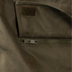 Detail view of a secure zippered waist pocket with robust construction on the military parka.
