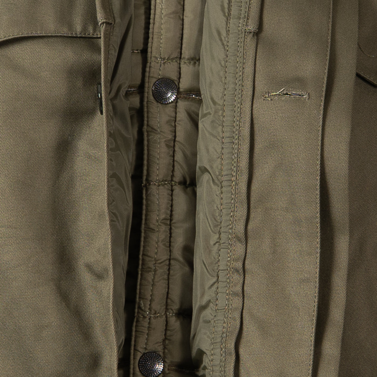 Detail of the internal popper button fastening system for the quilted liner inside the parka.