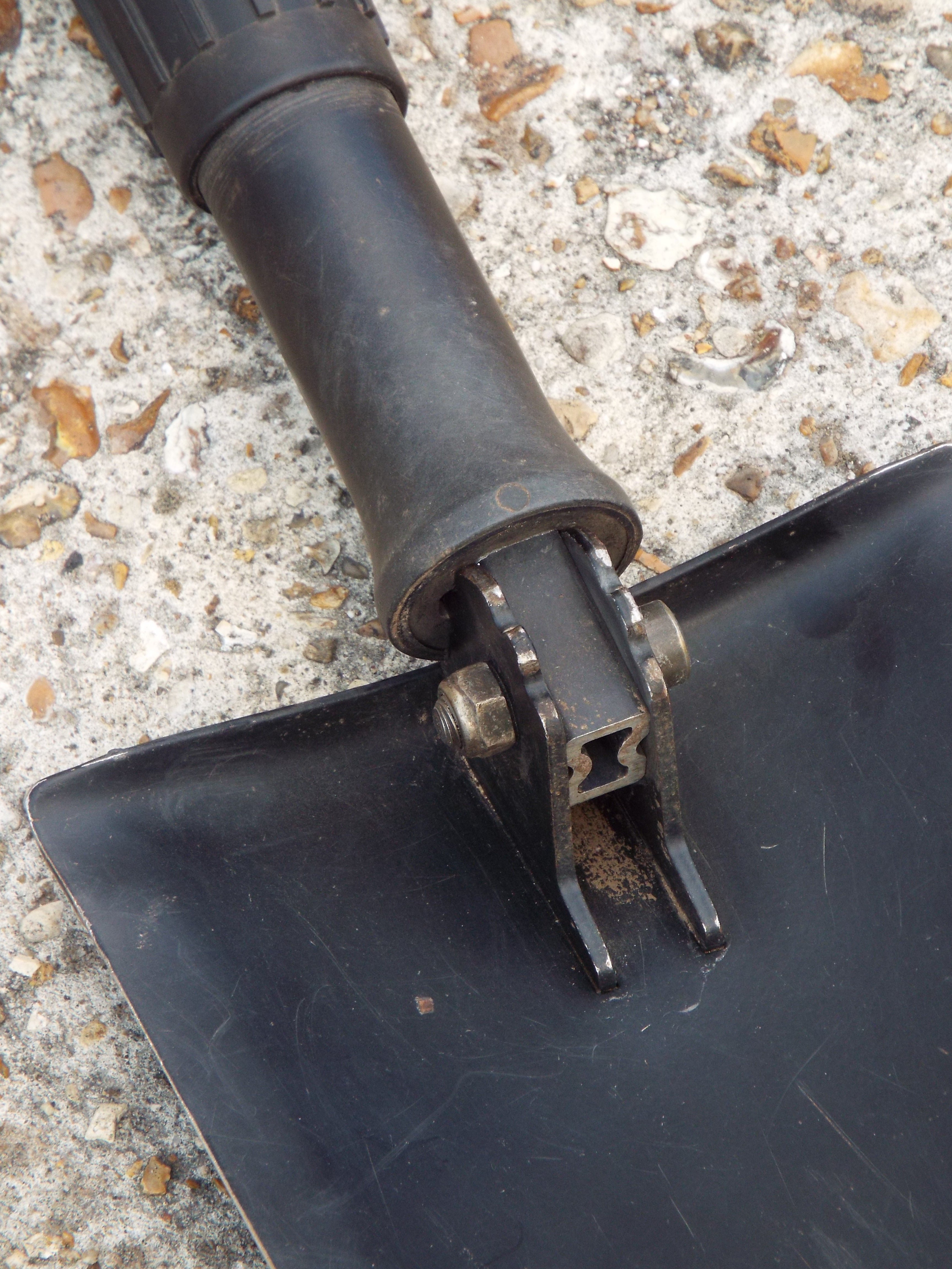 Detailed view of the shovel hinge mechanism and heavy-duty steel blade connection point on the military surplus E-Tool.