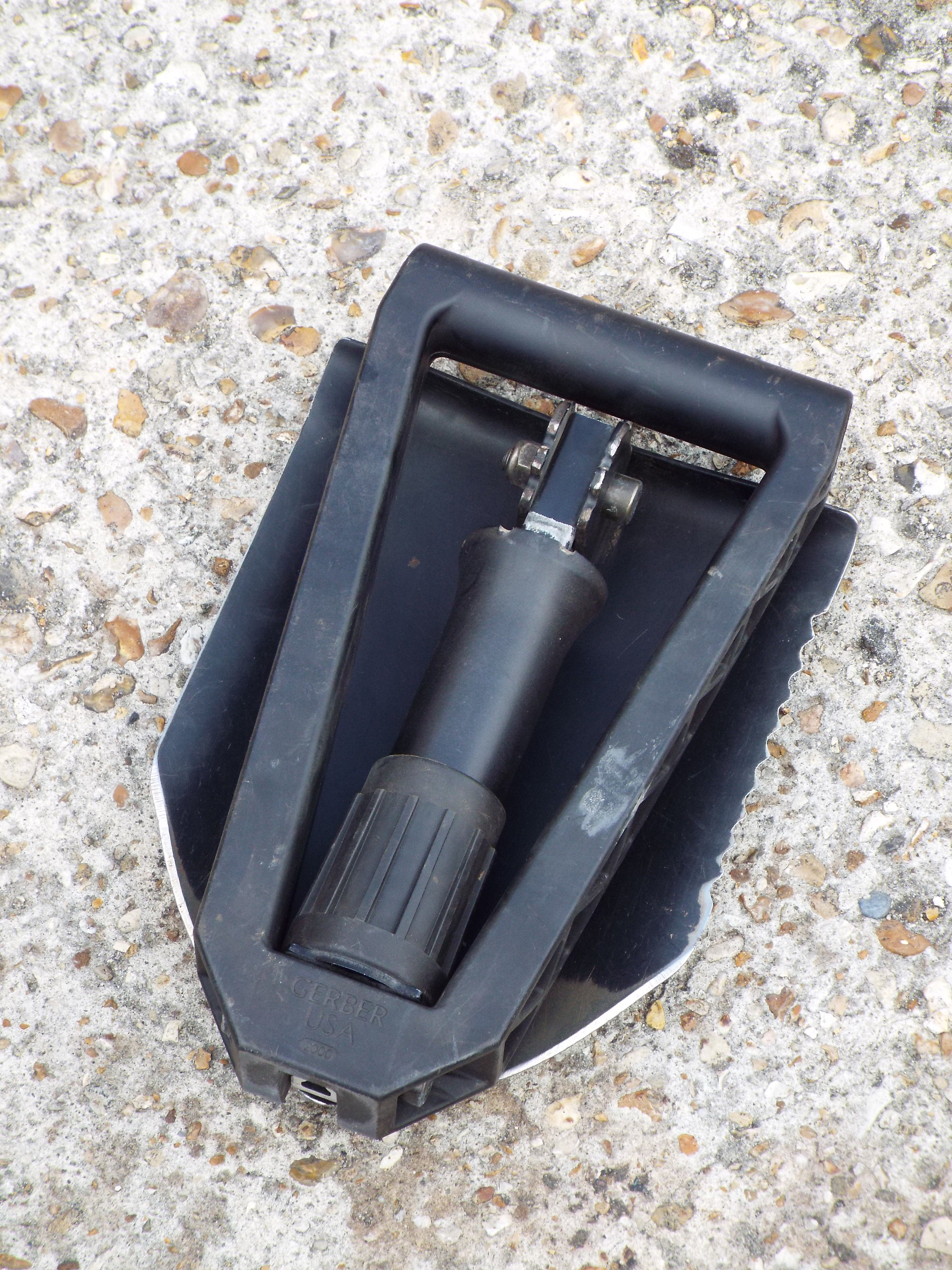 Compact folded Gerber E-Tool for easy transport, showing the serrated steel shovel blade and secure locking handle.