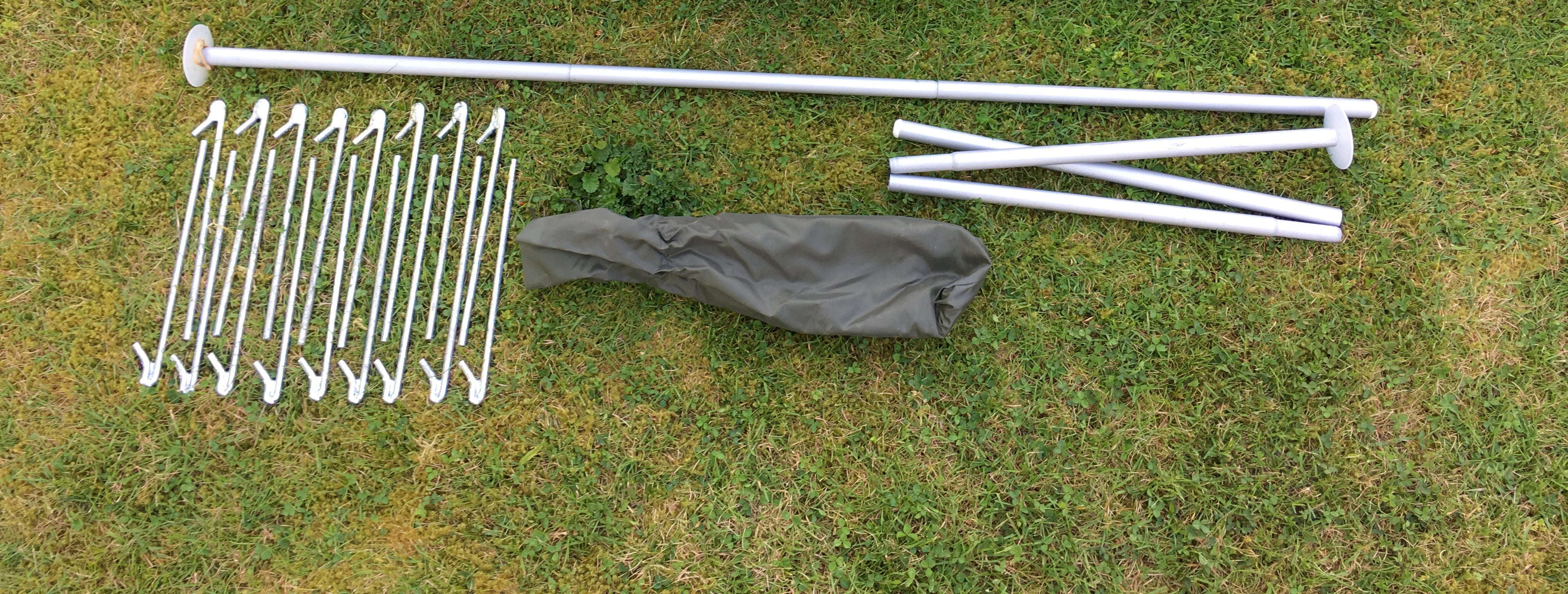 Bespoke nylon tent bag, modular poles, and steel pegs laid out on the grass.
