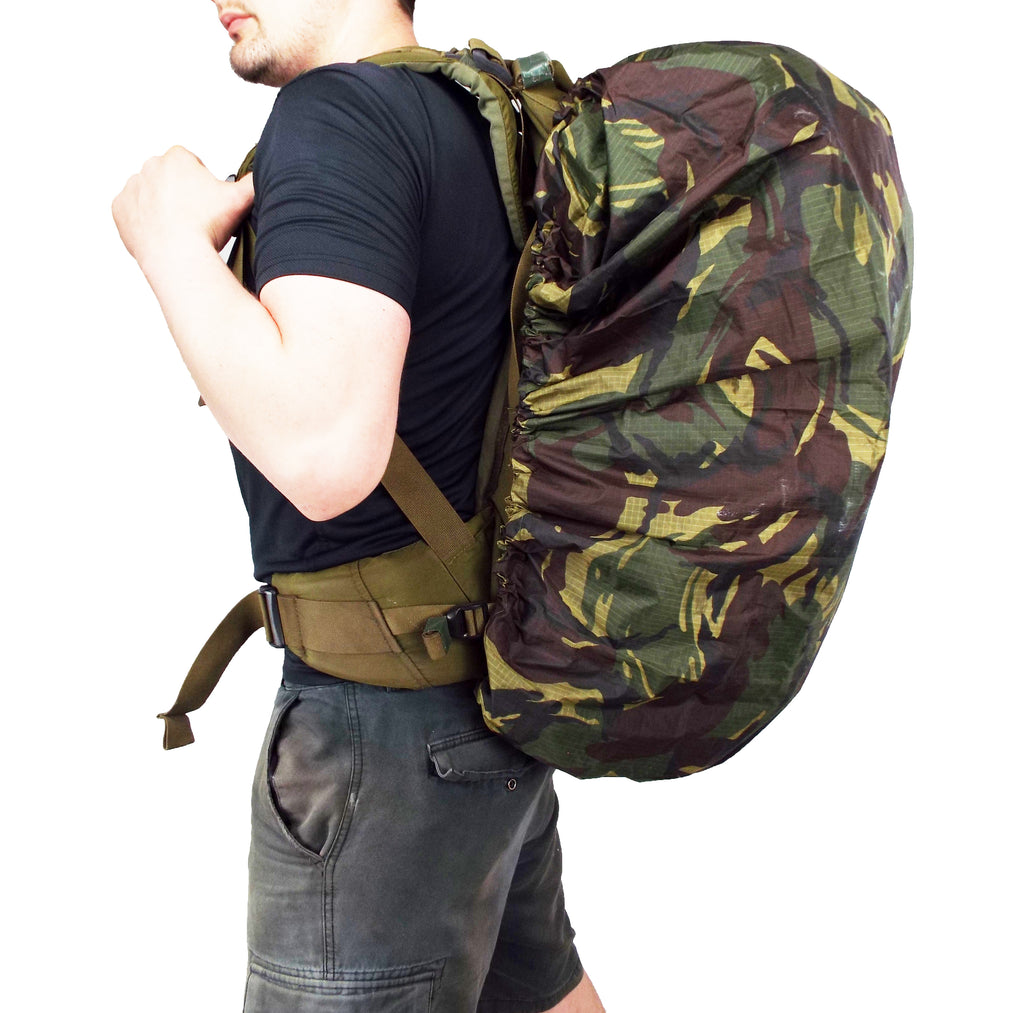 Side view of a person wearing a large backpack protected by a waterproof Dutch Army woodland camouflage Bergen cover.