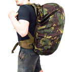 Side view of a person wearing a large backpack protected by a waterproof Dutch Army woodland camouflage Bergen cover.
