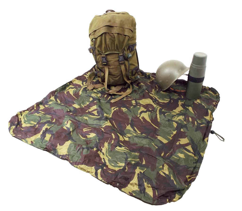 A full backpack, helmet, and flask placed on an unfolded Dutch Army woodland camouflage Bergen cover used as a ground sheet.