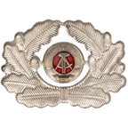 Front view of original East German NVA officers cap badge showing silver oak leaf wreath and DDR national emblem
