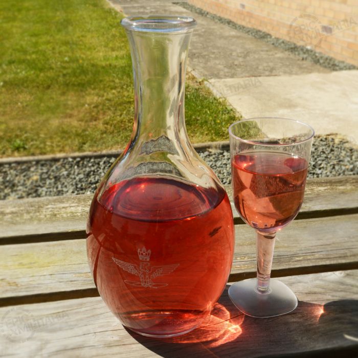 Italian Air Force glass carafe on outdoor wooden table next to filled glass