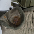 Extreme close up of a rusted steel snap fastener button on the Greek M56 canvas canteen cover showing oxidation