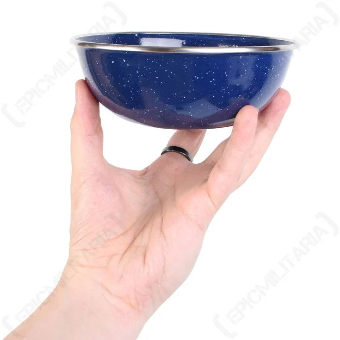 Blue enamel camp bowl held in hand showing deep shape and steel rim detail.