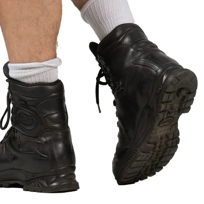 Rear angle view of the Haix combat boots being worn, highlighting the low scalloped back collar and the textured Vibram heel sole.
