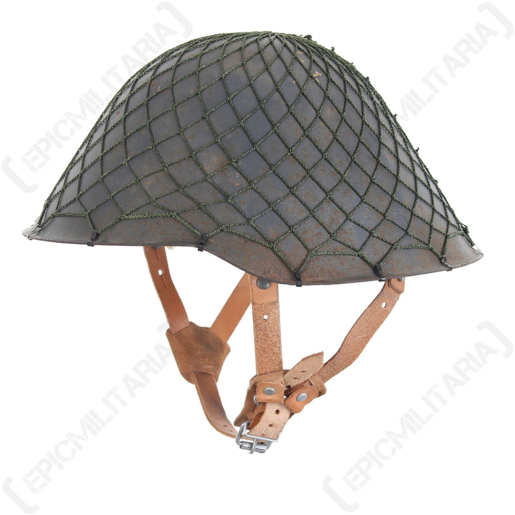 A side-profile view of a military helmet featuring an olive drab NVA camouflage net fitted securely over the shell.