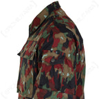Detail view of the left sleeve on the Swiss M83 Alpenflage jacket, highlighting the buttoned utility pocket, shoulder epaulette, and authentic woodland camo pattern.