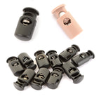 Genuine British Army surplus cord stoppers featuring durable plastic construction with spring-loaded mechanisms, displayed in black and tan color options.