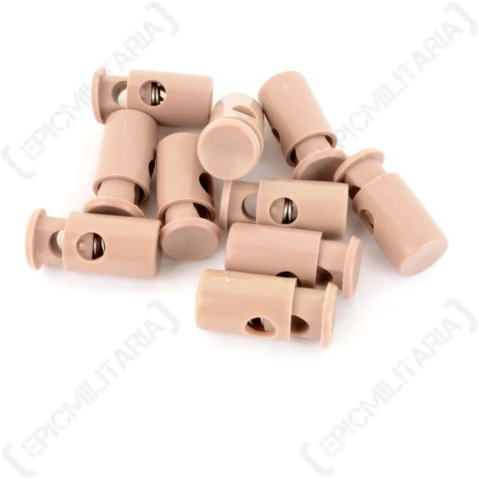Group of khaki-colored British Army cord stoppers showing the spring mechanism, two-hole design, and durable plastic build used for gear and equipment.