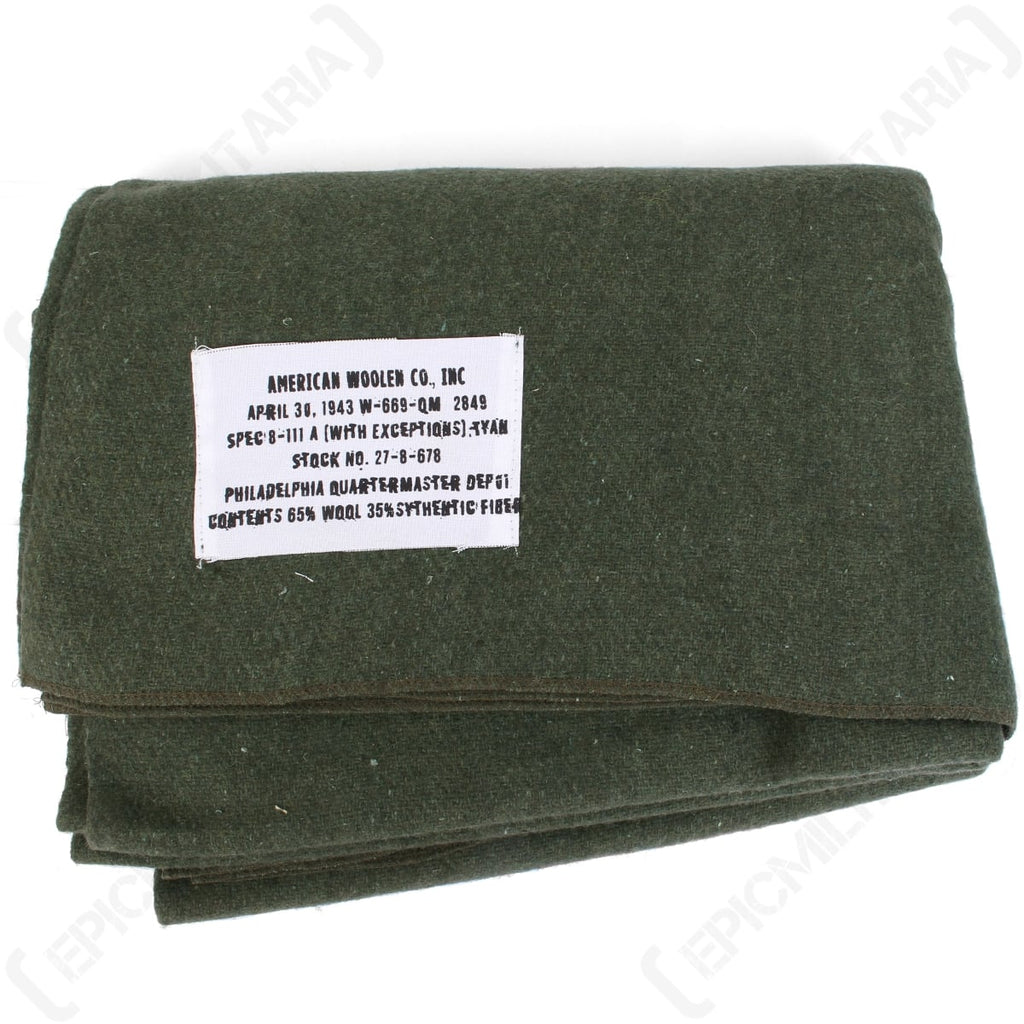 Top-down view of the olive green 1943 US Army reproduction wool blanket showing the official American Woolen Co., Inc. tag.