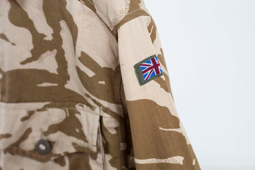 Close-up of the Union Jack flag patch on the sleeve of a genuine British military desert combat shirt.