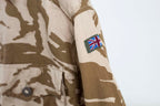 Close-up of the Union Jack flag patch on the sleeve of a genuine British military desert combat shirt.