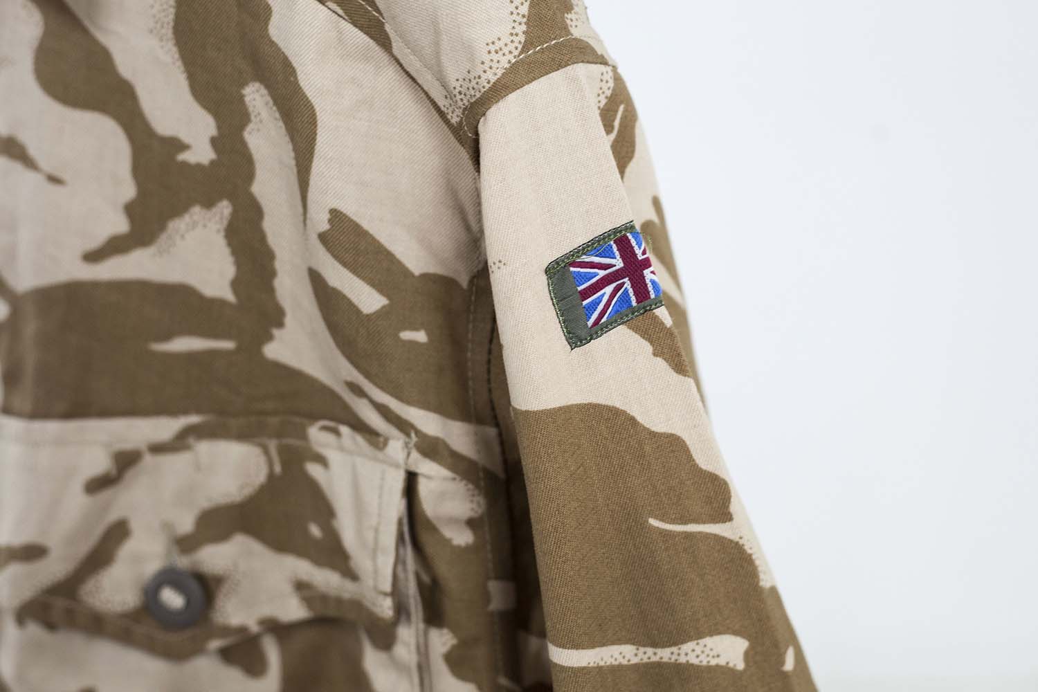 Close-up of the Union Jack flag patch on the sleeve of a genuine British military desert combat shirt.