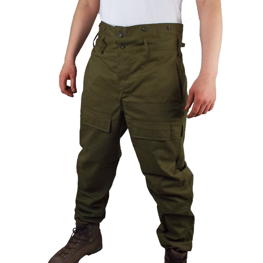 Model wearing Czech Cold Weather Combat Over-Trousers in olive green, featuring a high-waisted button design, side pockets, and durable cotton-polyester blend.