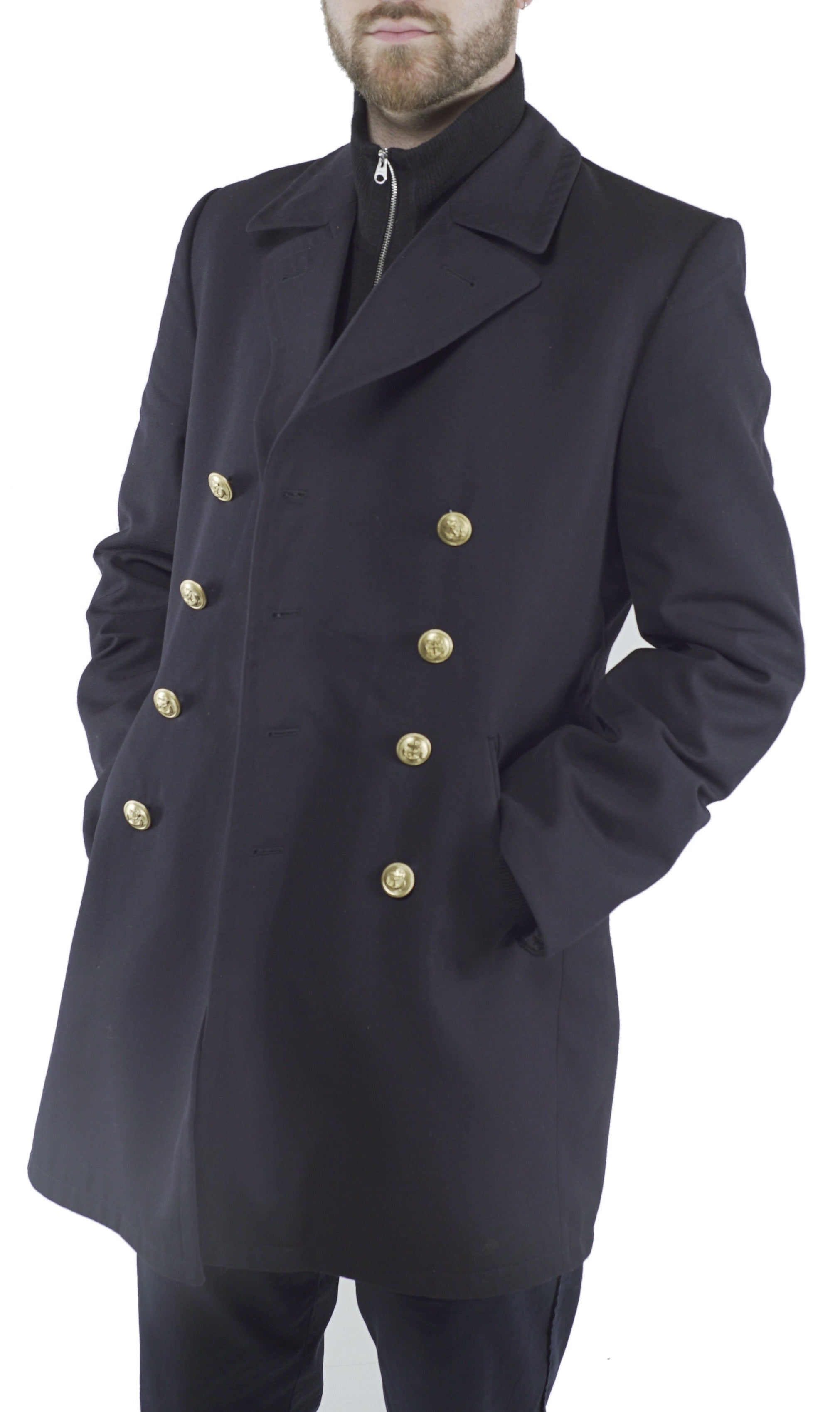 Man wearing a black German Navy gabardine peacoat with anchor emblem double-breasted gold buttons and hands in pockets.