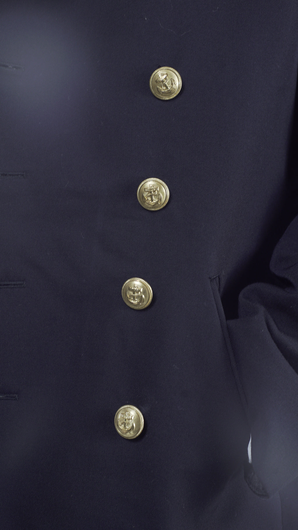 Close-up detail of the gold anchor emblem buttons on the black gabardine fabric of a German Navy peacoat.