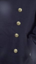 Close-up detail of the gold anchor emblem buttons on the black gabardine fabric of a German Navy peacoat.