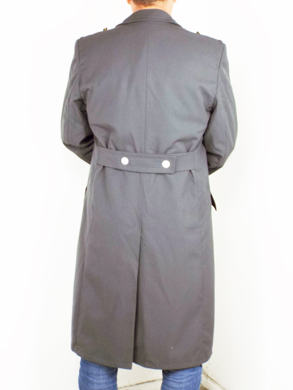 Rear view of a German army surplus trench coat featuring a half belt detail with two silver buttons and a central vent.