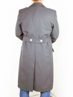 Rear view of a German army surplus trench coat featuring a half belt detail with two silver buttons and a central vent.