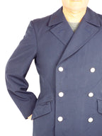 Close-up of the trench coat torso and arm, focusing on the dark blue gabardine texture, silver buttons, and front pocket placement.