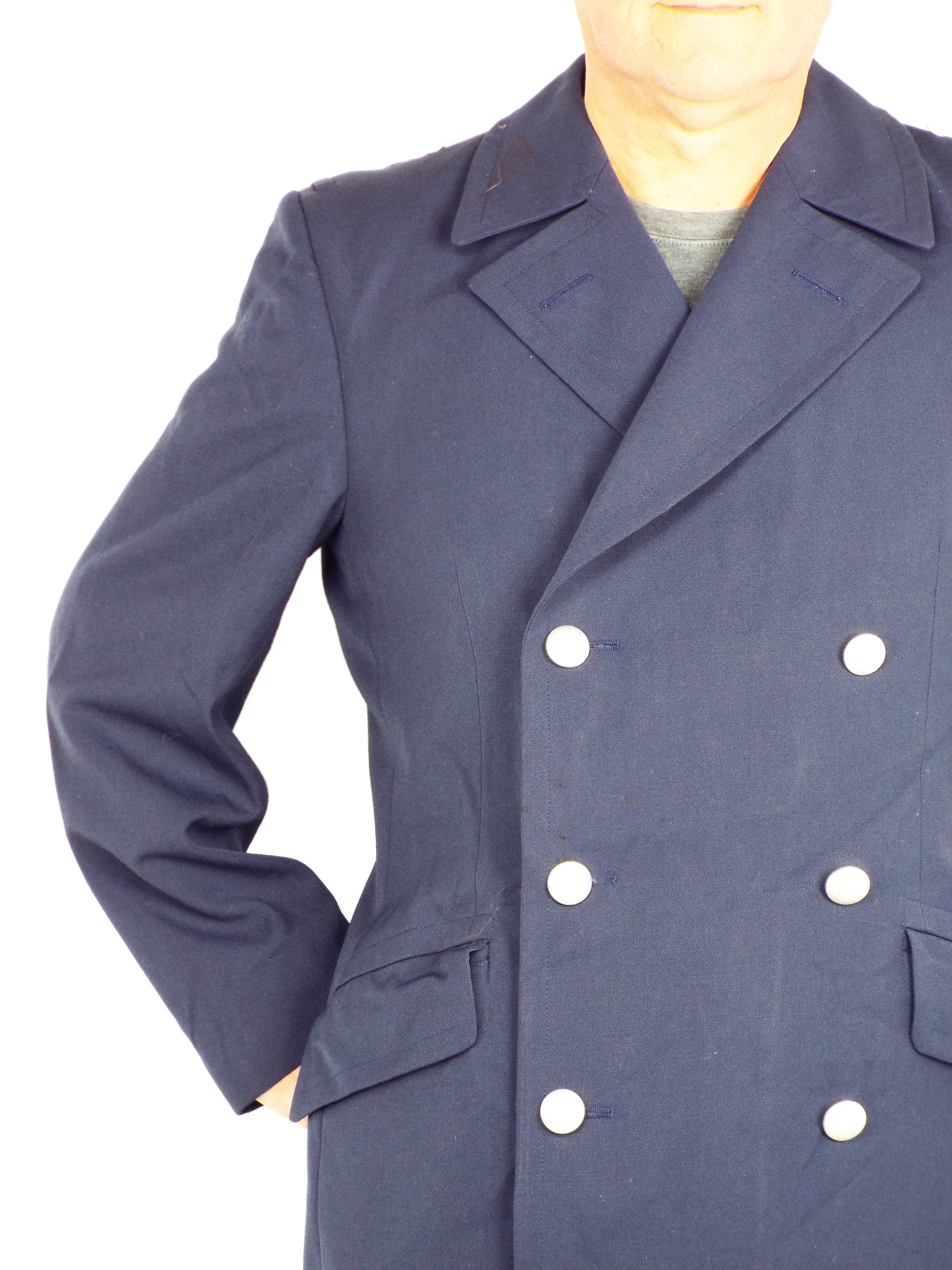 Close-up of the trench coat torso and arm, focusing on the dark blue gabardine texture, silver buttons, and front pocket placement.