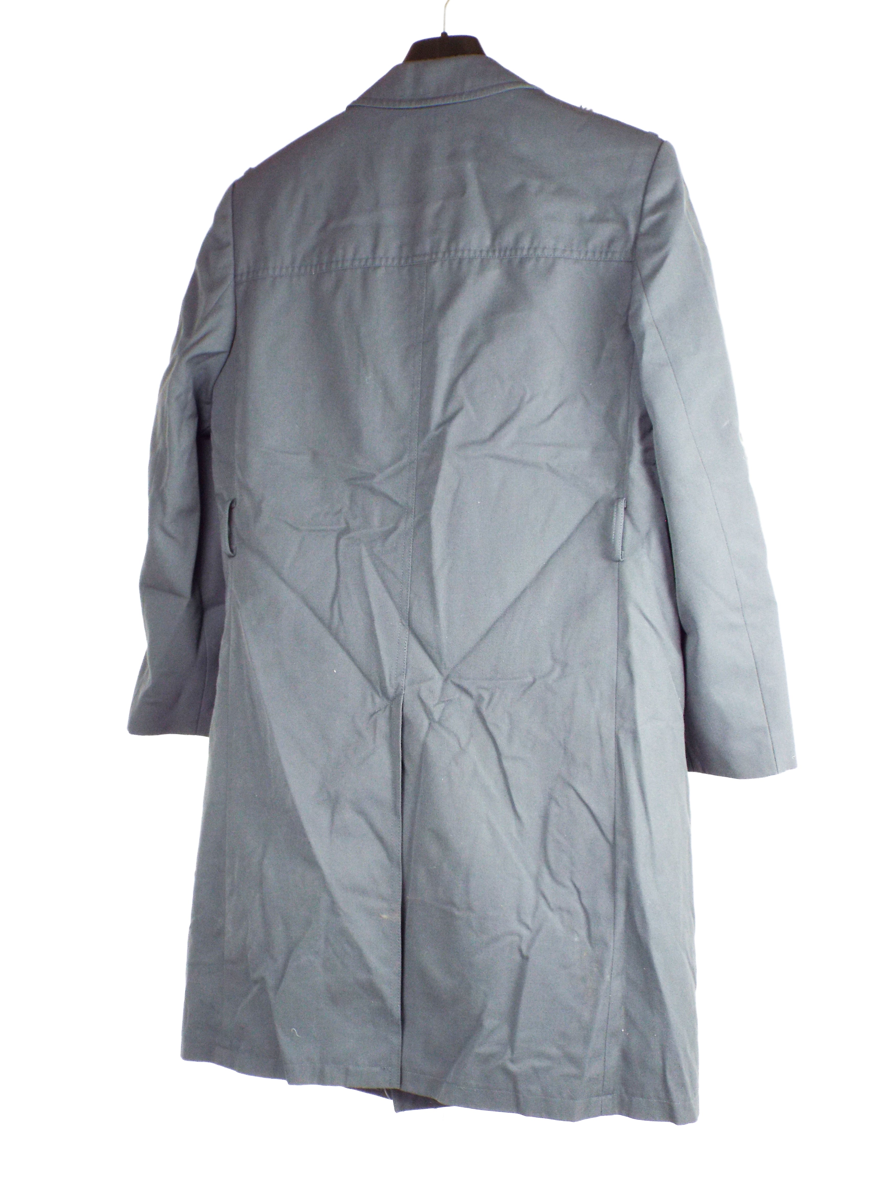 Rear view of the grey military trench coat, showing the classic back design, central vent, and durable gabardine fabric material.