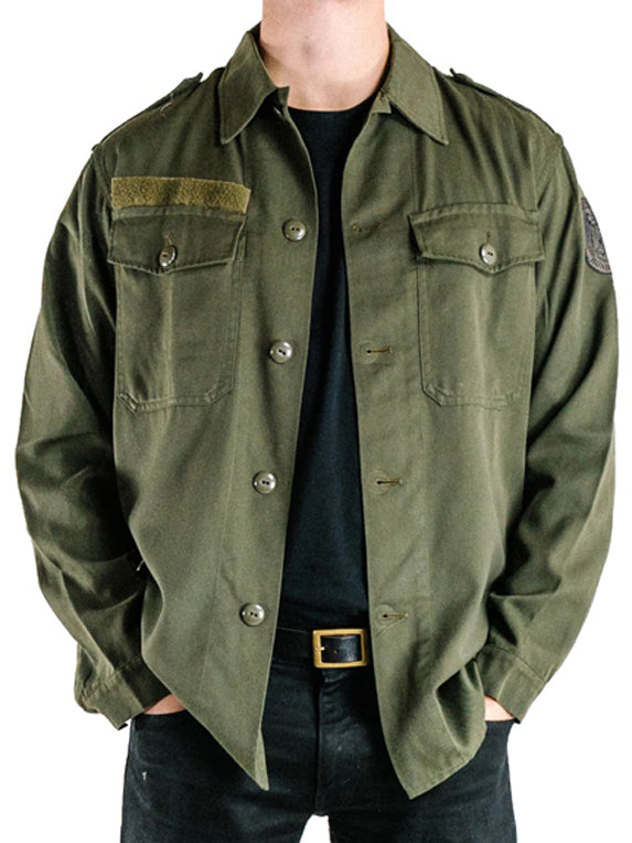 Close-up front view of a vintage Austrian army olive combat shirt with dual breast pockets, epaulets, and a velcro strip.