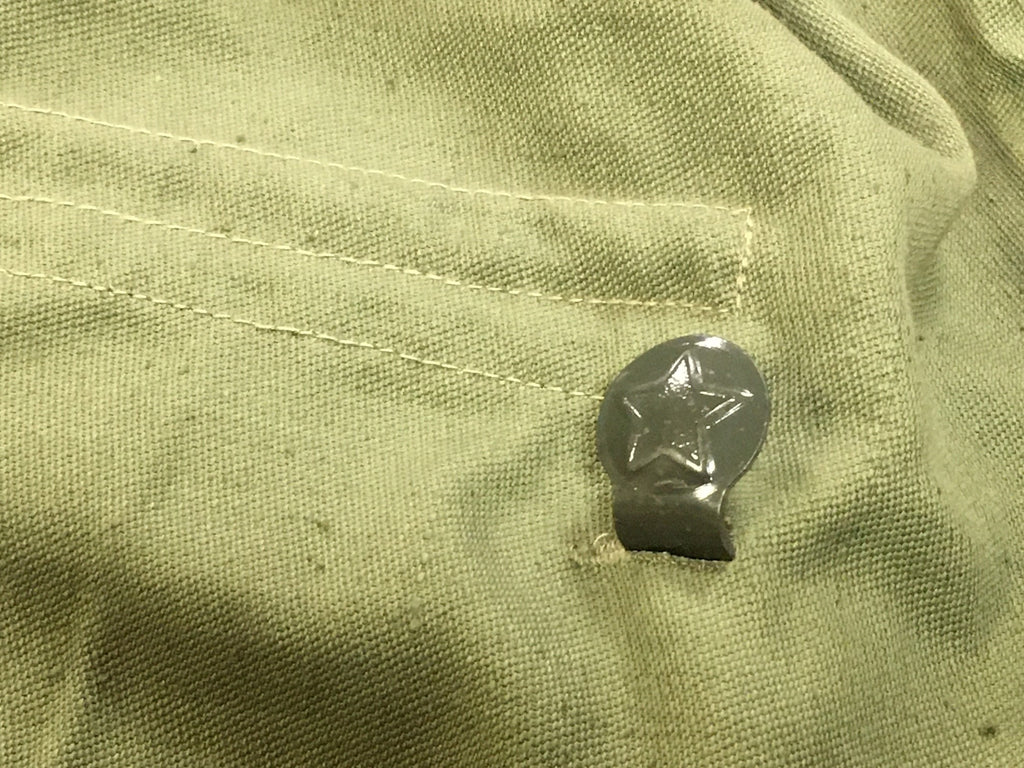 Detailed view of a metal waist hook embossed with the socialist star on a Bulgarian military shirt.