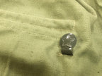 Detailed view of a metal waist hook embossed with the socialist star on a Bulgarian military shirt.