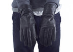 Front view of black French army surplus leather gloves worn by a person in a striped top.