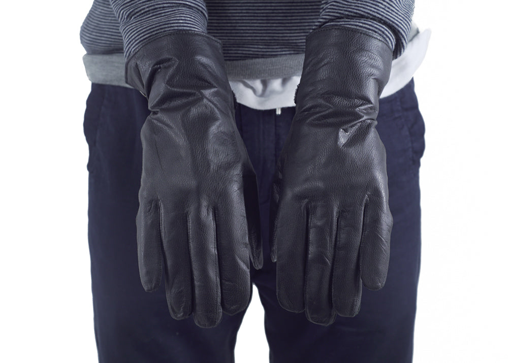 Front view of black French army surplus leather gloves worn by a person in a striped top.