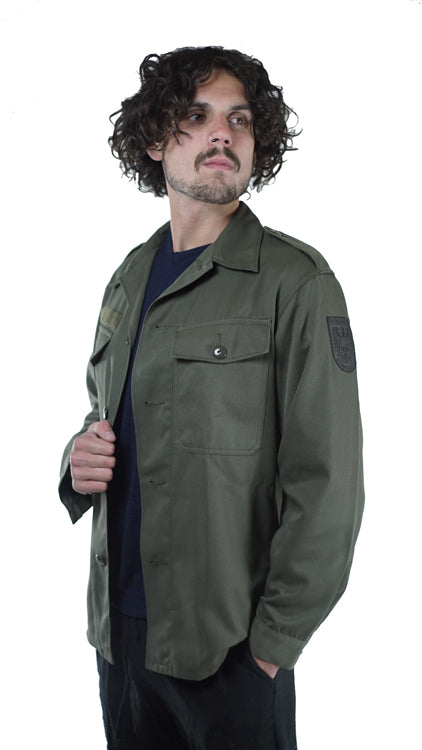 Side-angle view of a man wearing the olive green Austrian army combat shirt with visible shoulder epaulets and sleeve patch.