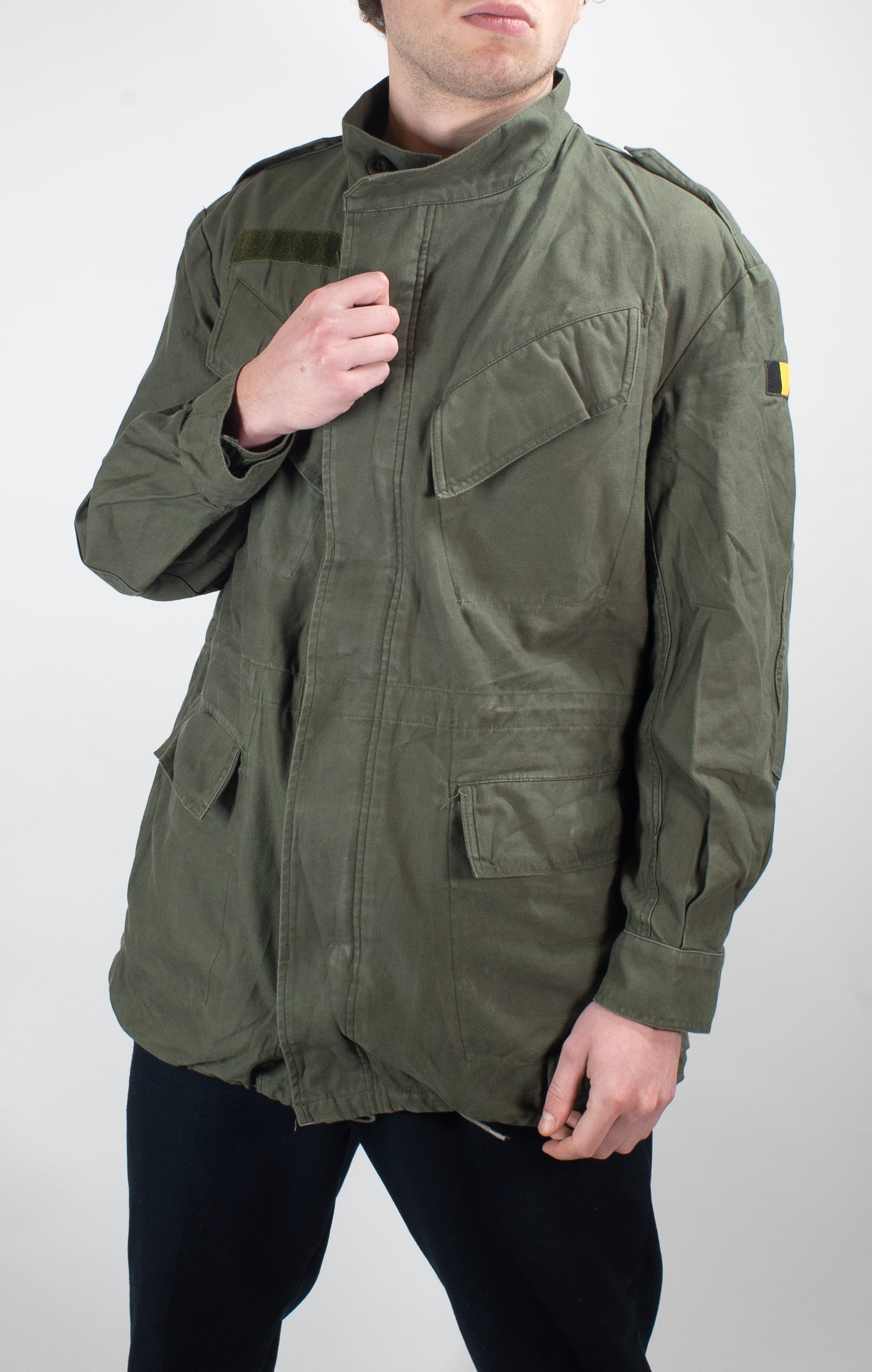 Mens Belgian army olive green field jacket showing shoulder epaulets, zip fastening with buttoned wind flap, and national flag patch on the sleeve.