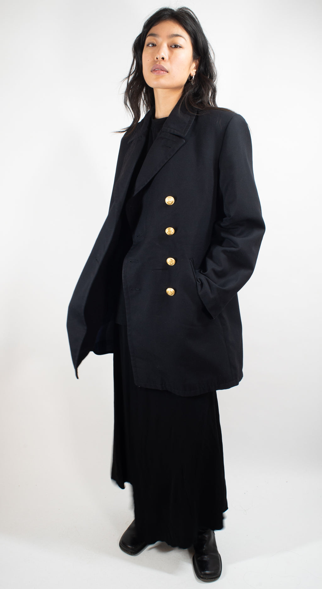 Woman modeling a black German Navy gabardine peacoat from a side angle, showing the length and double-breasted silhouette.