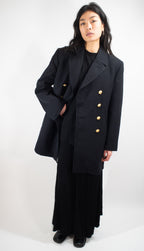 Woman wearing a black German Navy gabardine peacoat with hands in pockets, displaying the fit and lapel detail.
