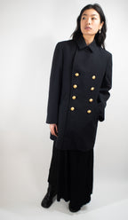 Woman wearing a black German Navy peacoat with the collar fastened, showcasing a clean, minimalist tailored look.