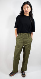 Front view of a person wearing durable British Army olive green trousers with pockets and dark athletic shoes.