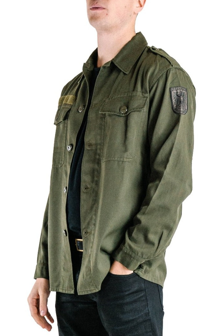 Side profile of the Austrian army olive combat shirt showing the embroidered military insignia on the sleeve and heavy cotton blend texture.