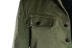 Detailed view of a scalloped chest pocket with an embossed pewter-colored socialist star button.